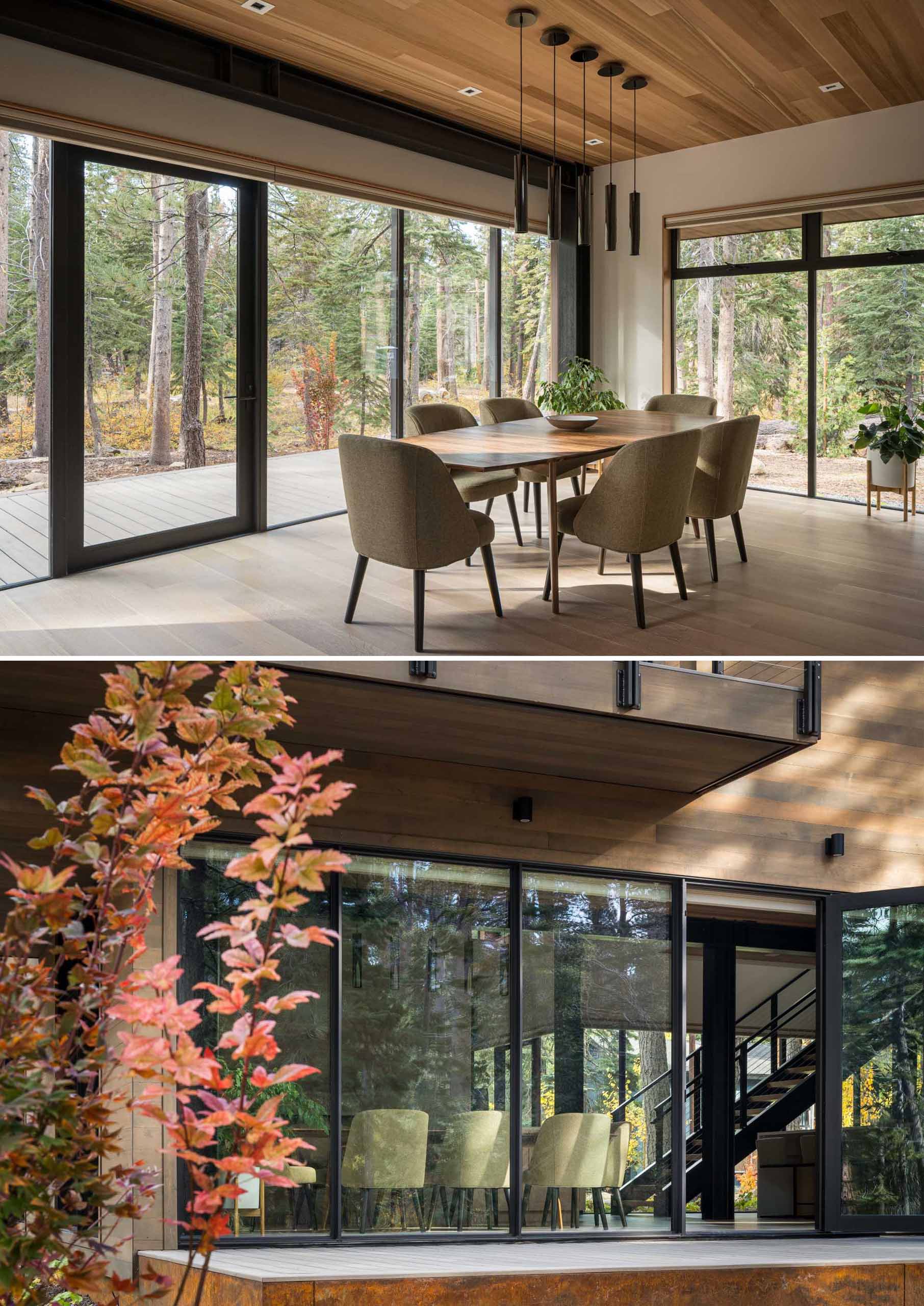 Floor-to-ceiling windows in this dining room frame the trees, while a door connects the interior to the deck outside.