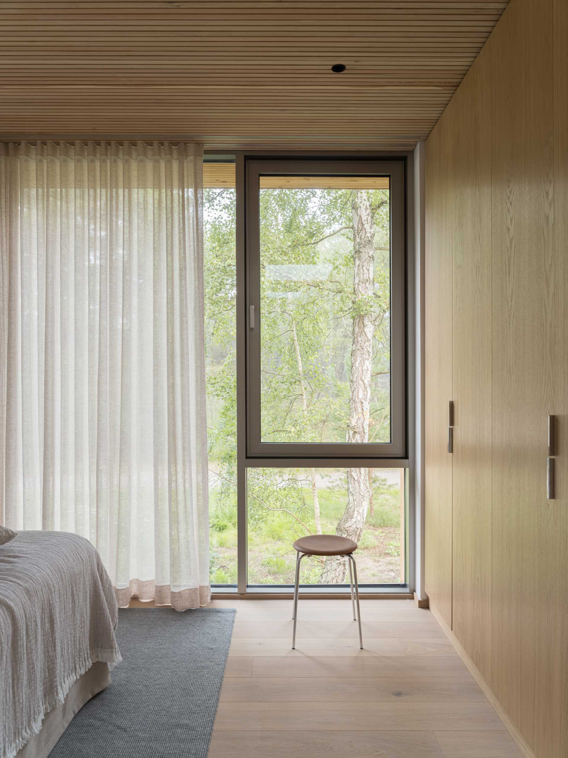 A modern bedroom with a wall of windows.