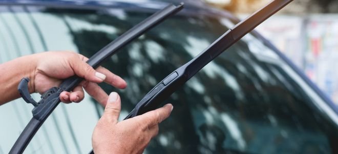 hands holding new wiper blades for replacement