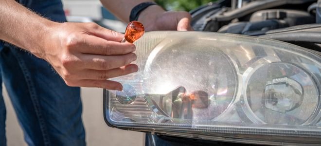 hand holding replacement bulb to change headlight