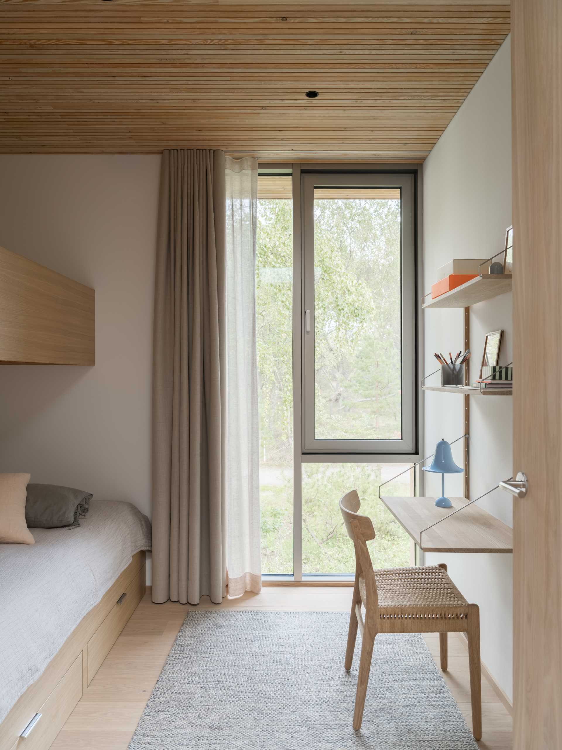 A modern bedroom with a wall-mounted desk that also includes shelving above.