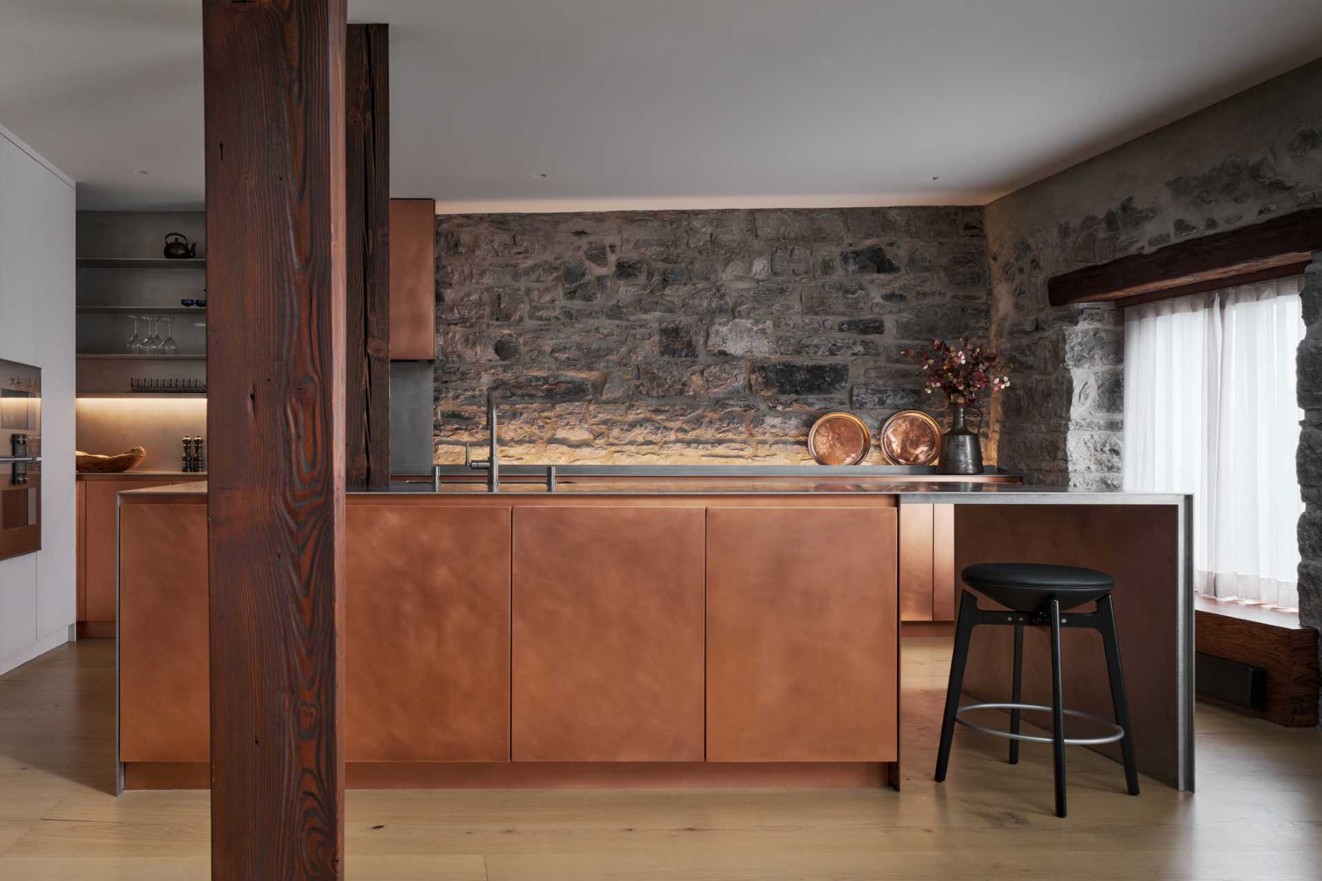 This modern kitchen in a renovated historic loft, features striking copper cabinetry and a stainless steel countertop.