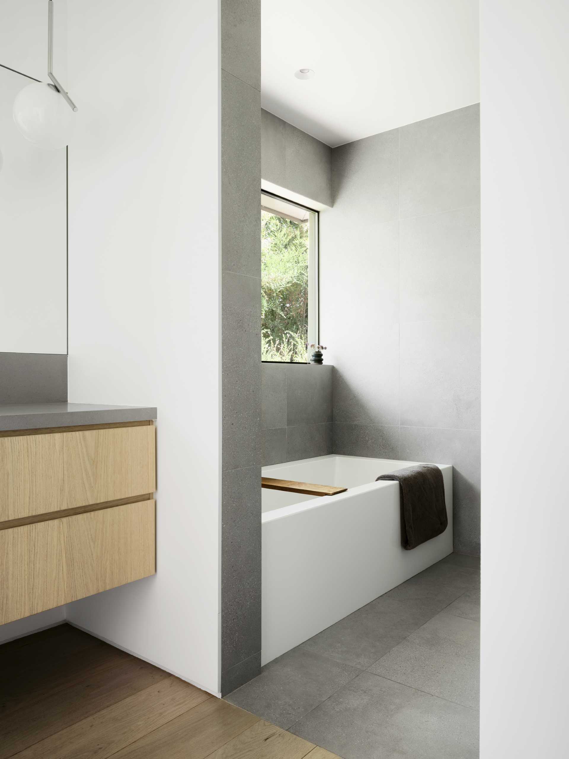 A contemporary bathroom with a grey, white, and wood appearance.