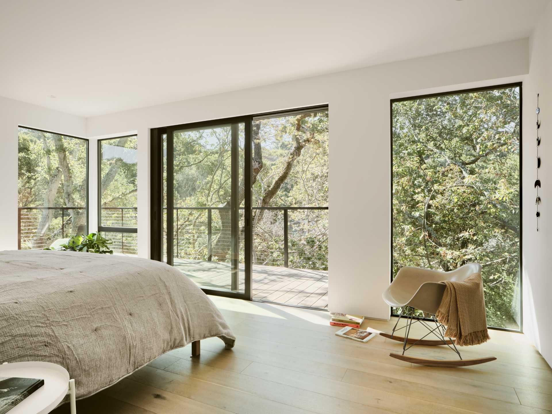 A modern bedroom opens up to a wrap-around deck.