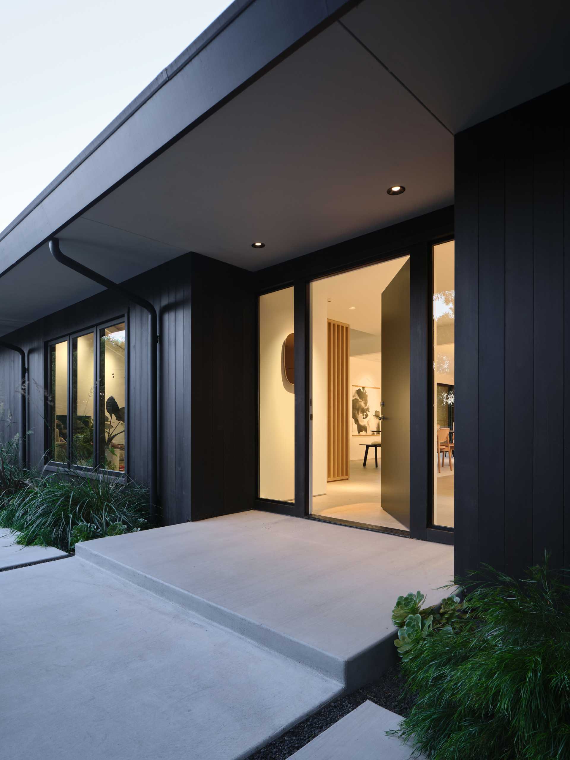 Updated cladding and roofing give the exterior of the home a sleek, modern feel while maintaining the low-slung ranch profile. In the front yard, low concrete walls and plantings create privacy from the street, complementing the architecture’s crisp, modern intervention.