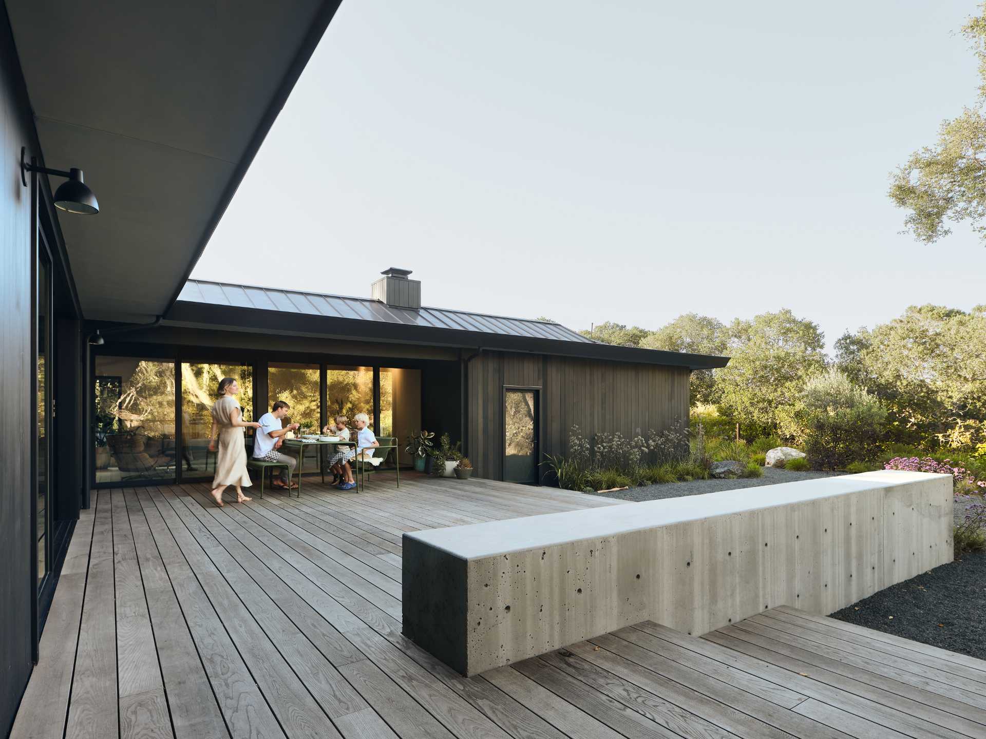 In the rear yard, an old patio and plain backyard was replaced with concrete walls that create two distinct, layered outdoor living spaces, emphasizing the new modern aesthetic and adding structure to the experience of the site and architecture.