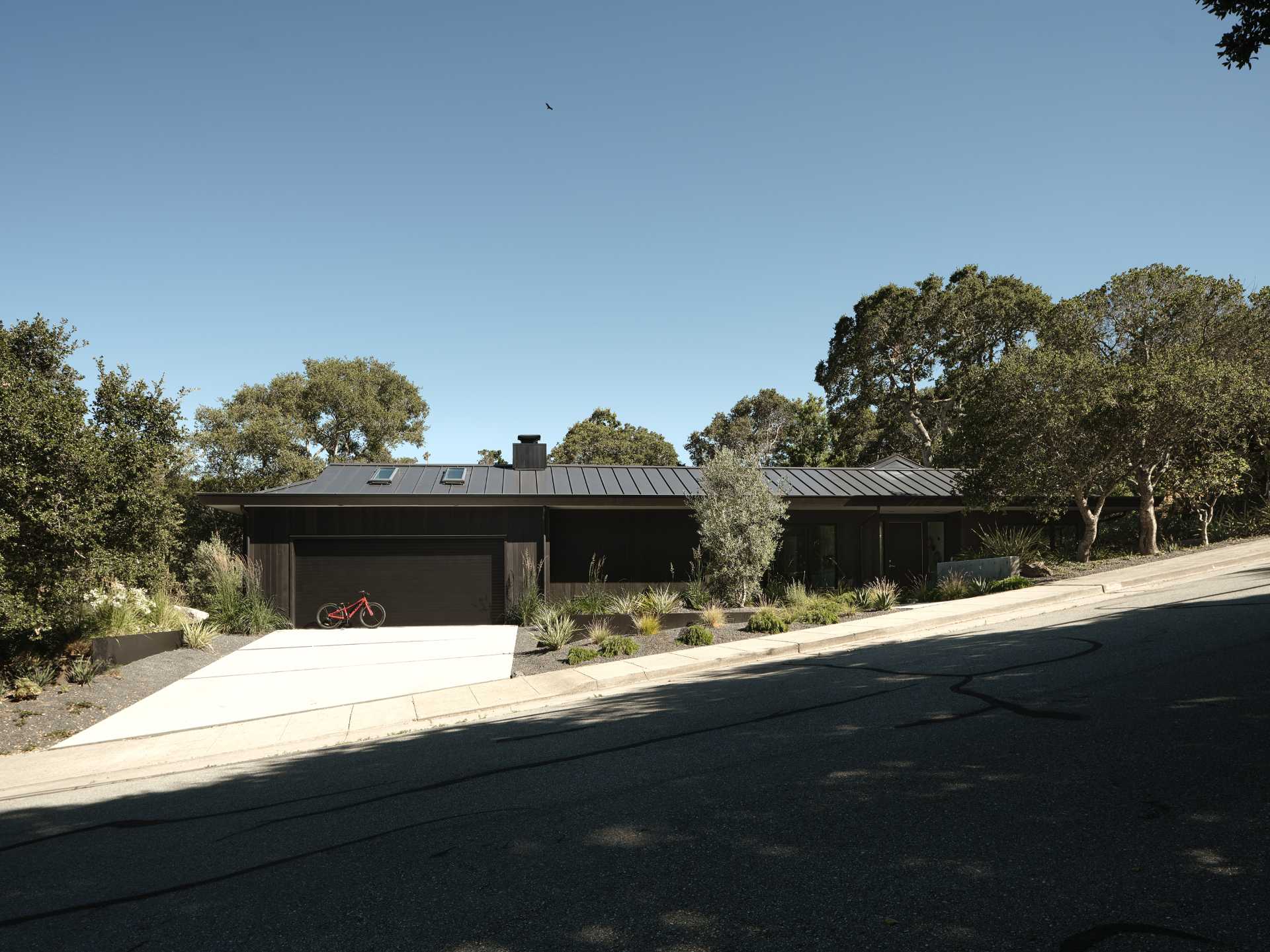 Updated cladding and roofing give the exterior of the home a sleek, modern feel while maintaining the low-slung ranch profile. In the front yard, low concrete walls and plantings create privacy from the street, complementing the architecture’s crisp, modern intervention.