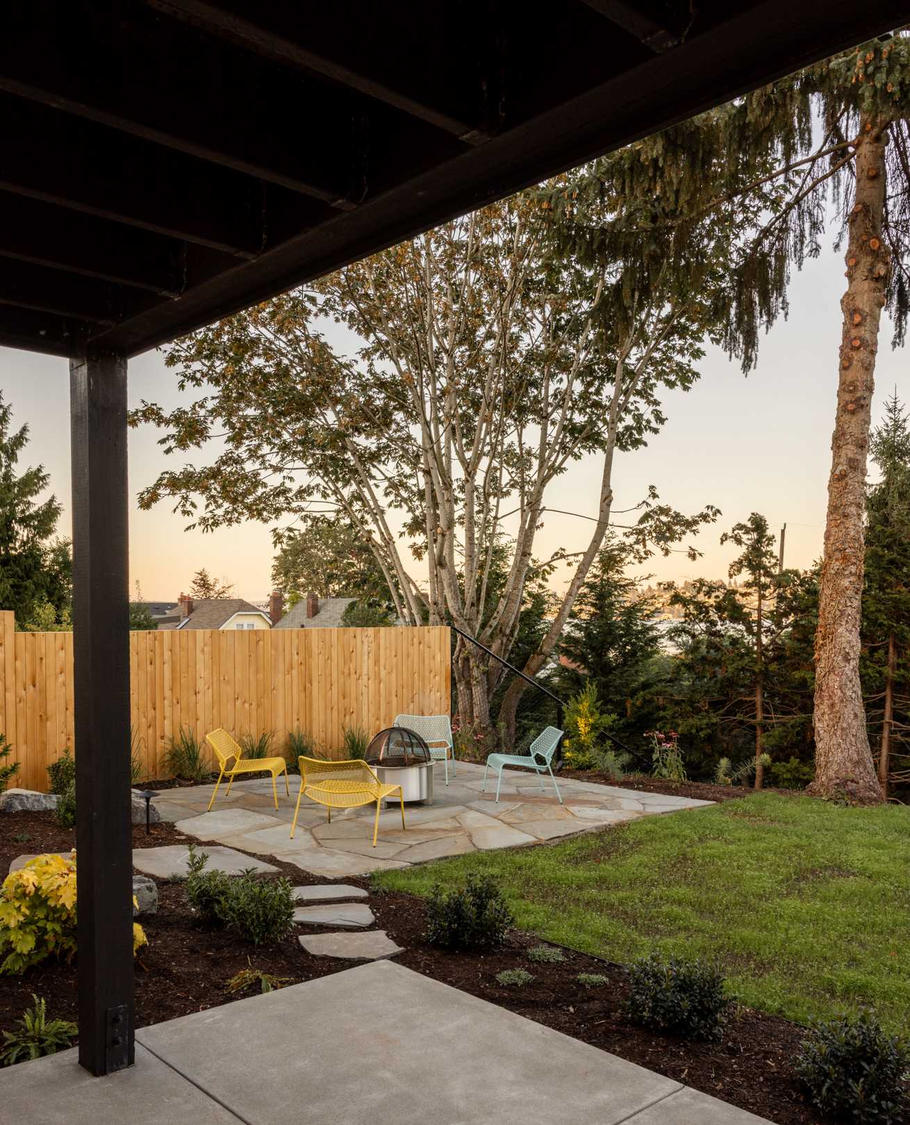 Elegant landscaping features carefully positioned stone patios encircled with native plants and trees, fenced areas for privacy, and stepping stones to the backyard, while the deck has stairs connecting to the garden.