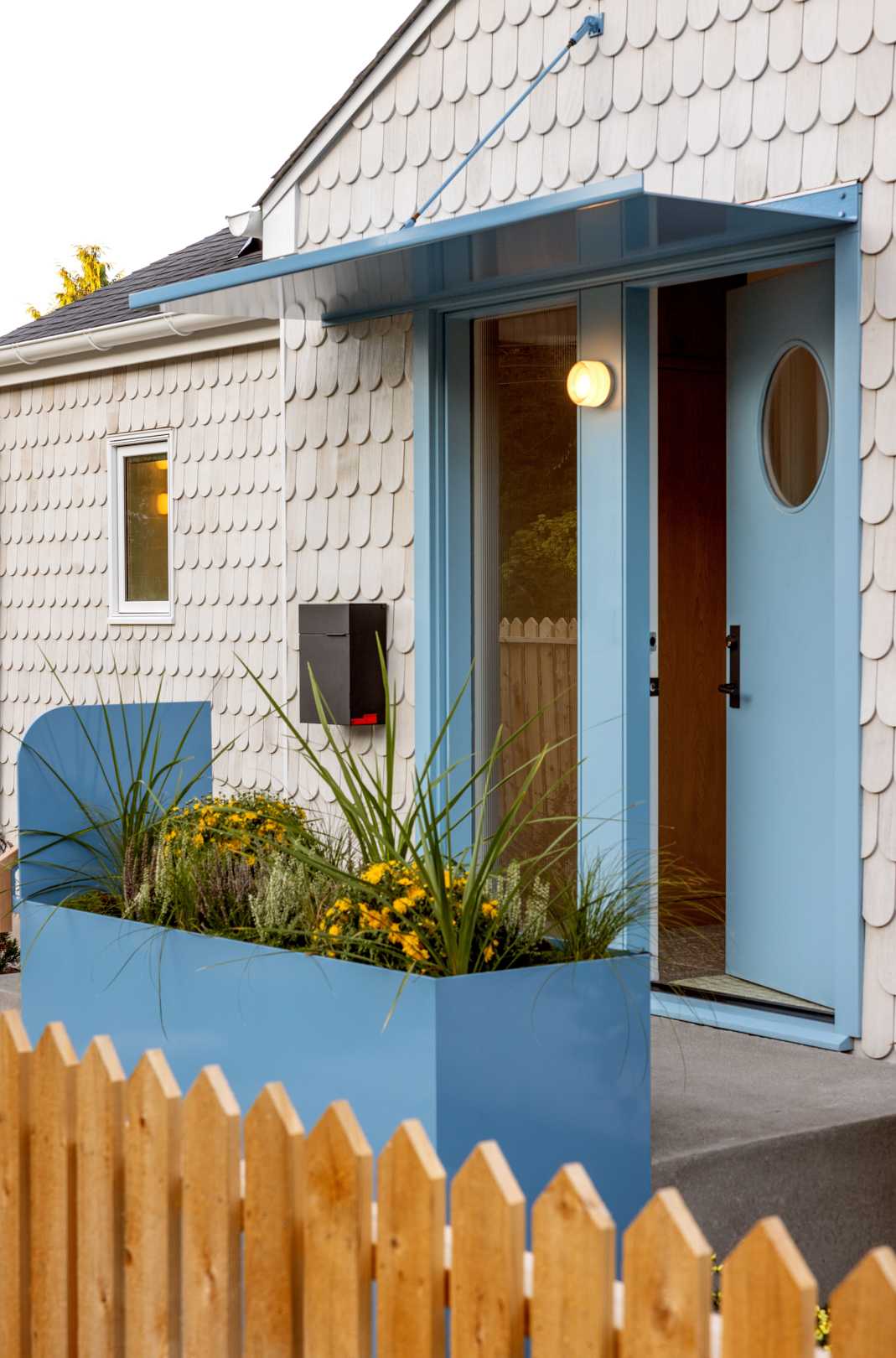 A renovated home with scalloped shingles and blue accents.