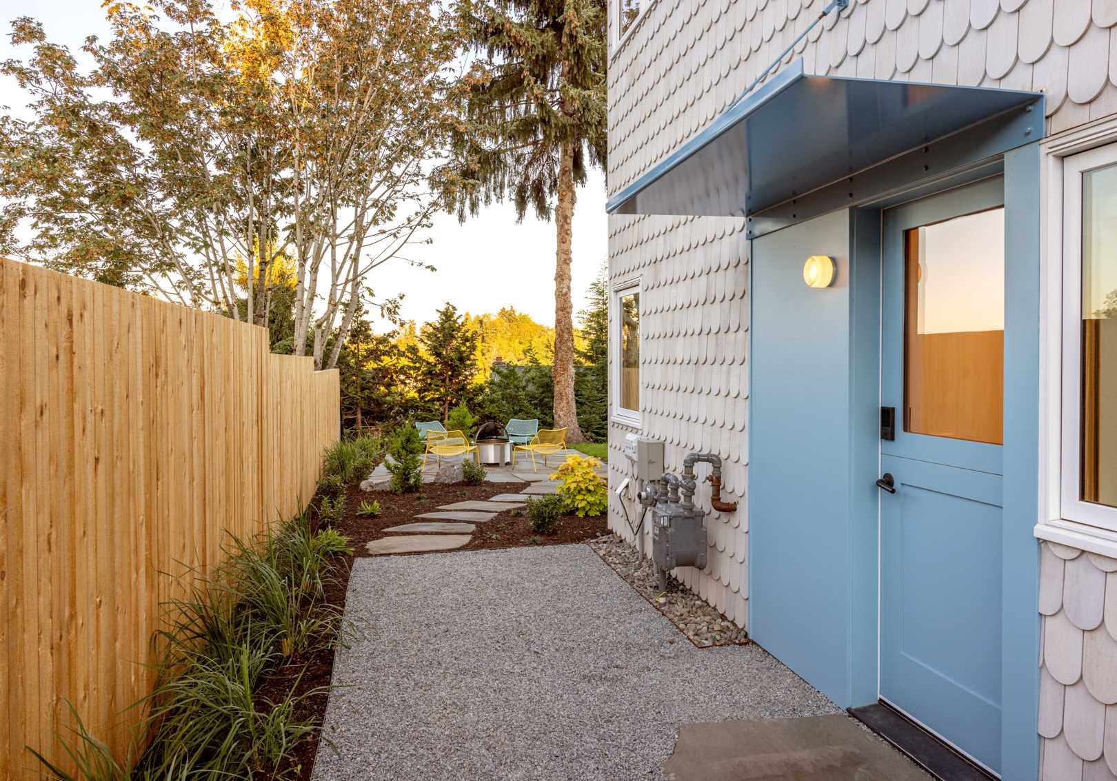 A renovated home with scalloped shingles and blue accents.