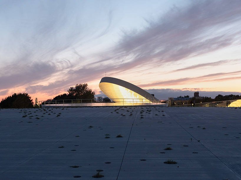 tilted reflective disk sits atop SMAR's science island museum in nemunas, lithuania