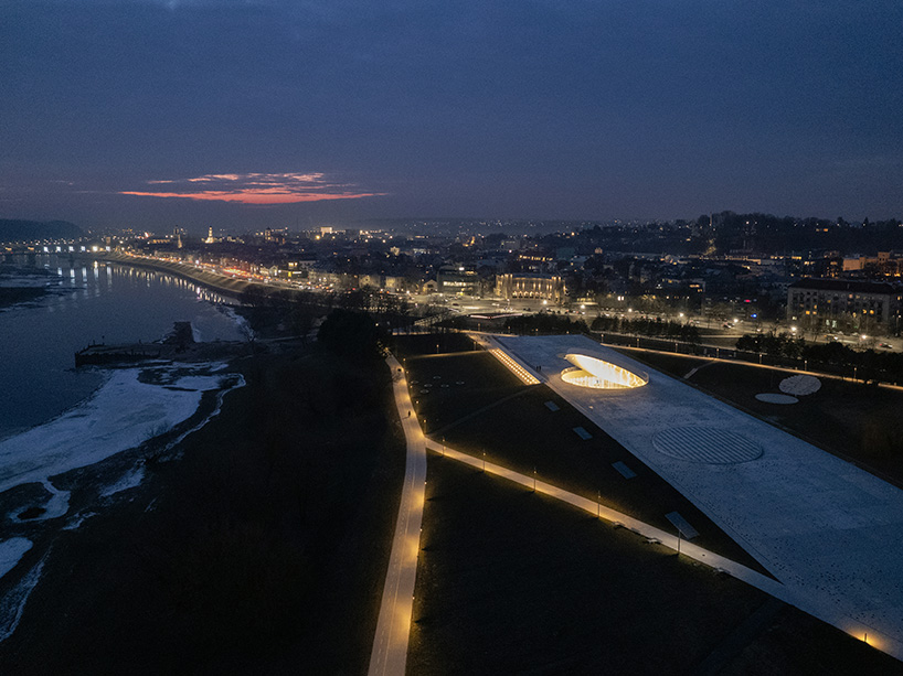 tilted reflective disk sits atop SMAR's science island museum in nemunas, lithuania