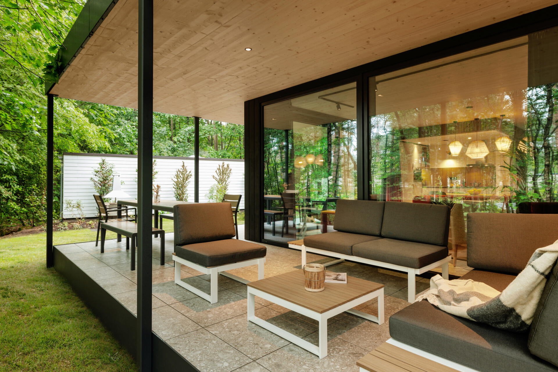 This modern prefab cottage features a private outdoor deck that extends into the woods, offering a peaceful spot to unwind and reconnect with nature.
