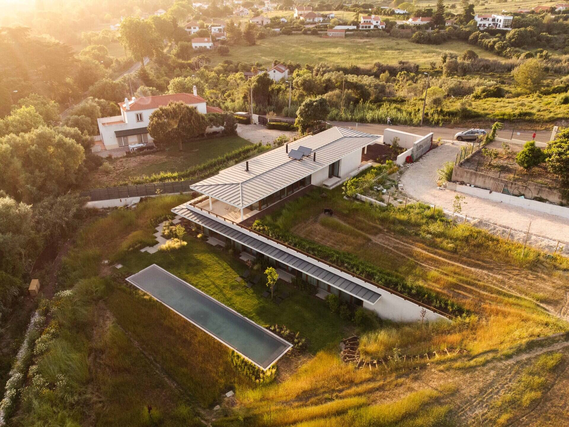 This hillside home uses the natural slope to its advantage. Half-buried and minimal in form, it blends seamlessly with its environment.  The green roof disappears into the landscape, helping regulate temperature while softening the structure’s visual impact.