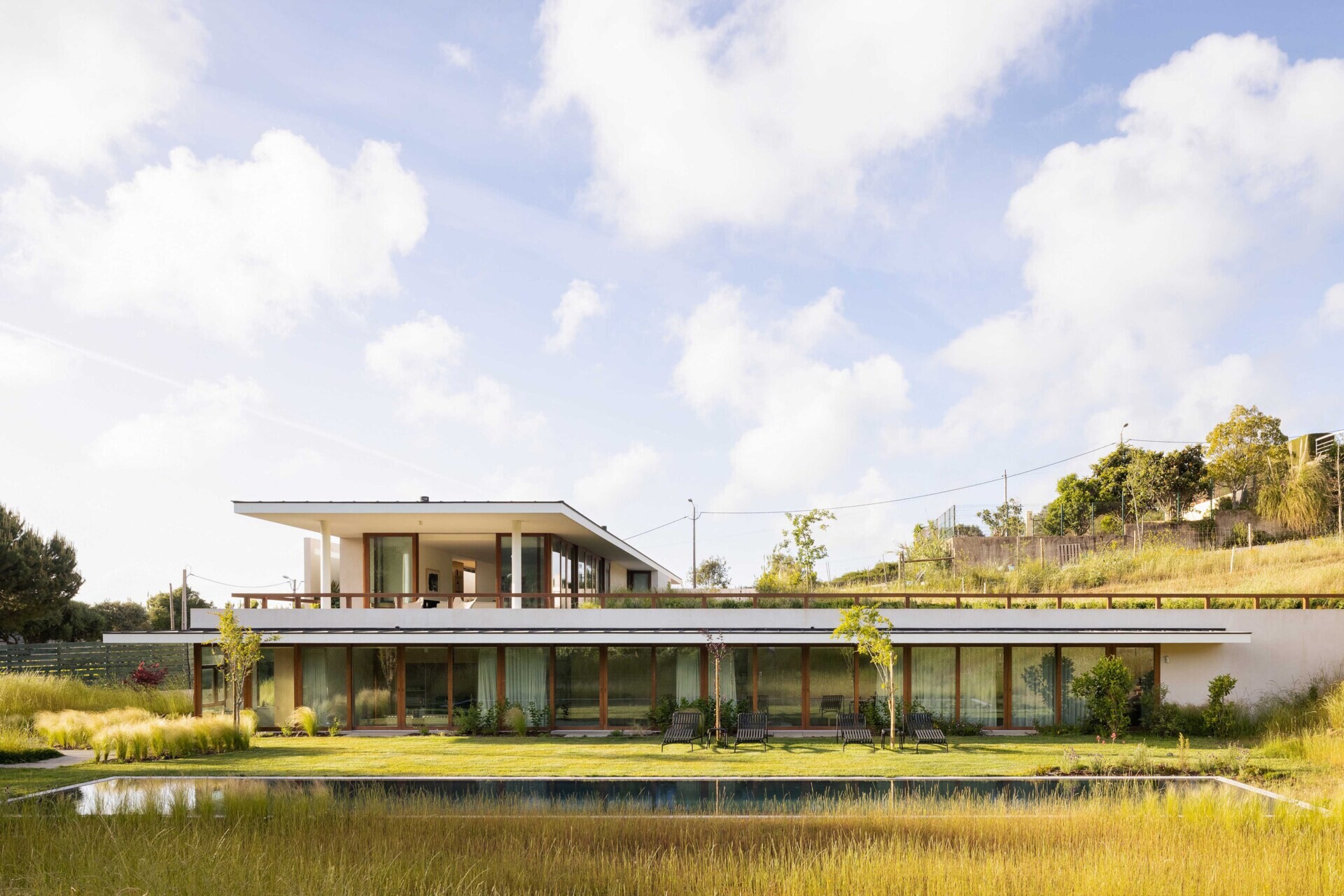 This hillside home uses the natural slope to its advantage. Half-buried and minimal in form, it blends seamlessly with its environment.  The green roof disappears into the landscape, helping regulate temperature while softening the structure’s visual impact.