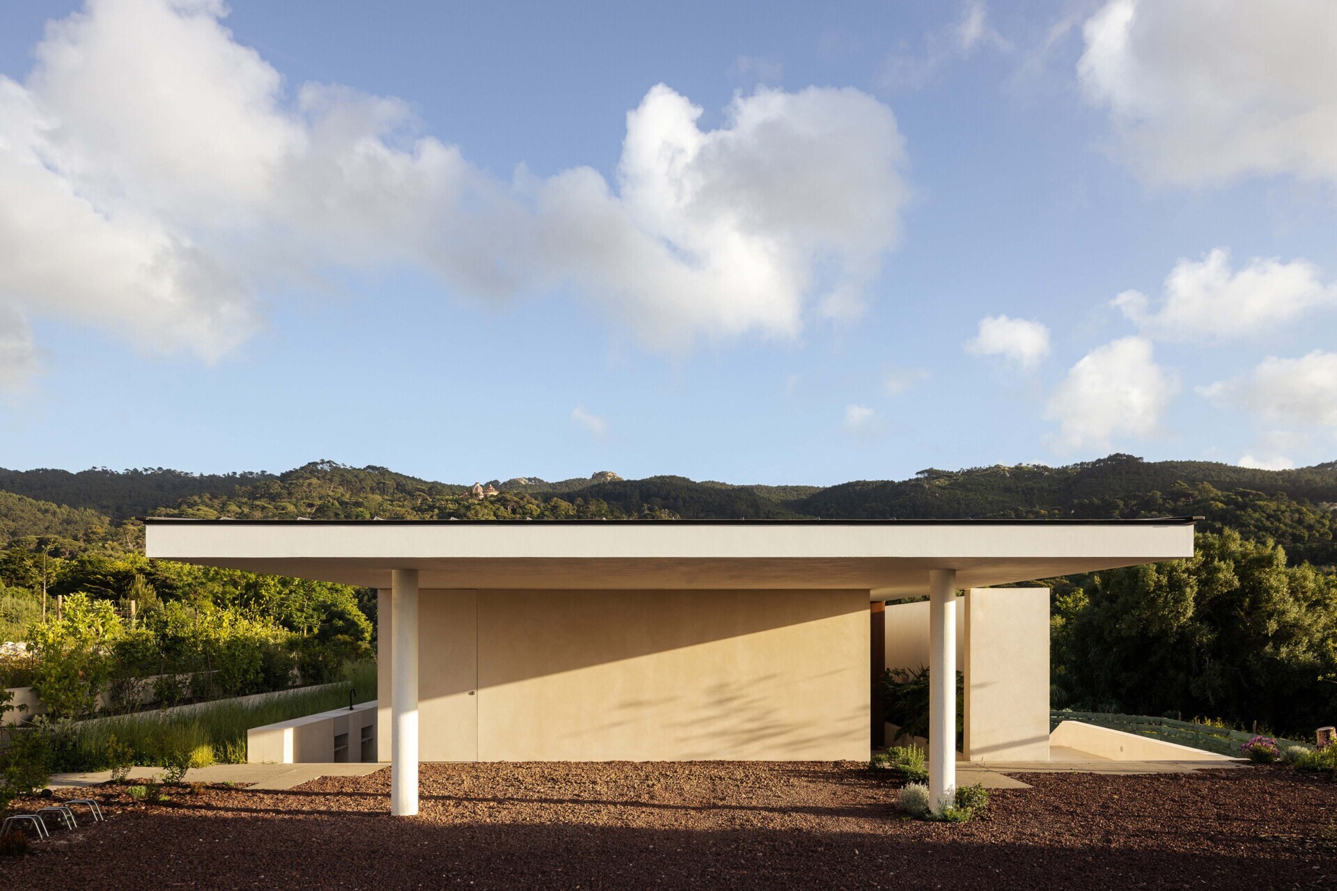 This hillside home uses the natural slope to its advantage. Half-buried and minimal in form, it blends seamlessly with its environment.  The green roof disappears into the landscape, helping regulate temperature while softening the structure’s visual impact.