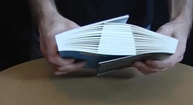 Hands holding a partially open book on a table.
