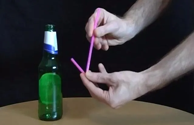 Demonstration of two pink straws positioned near a green glass bottle.