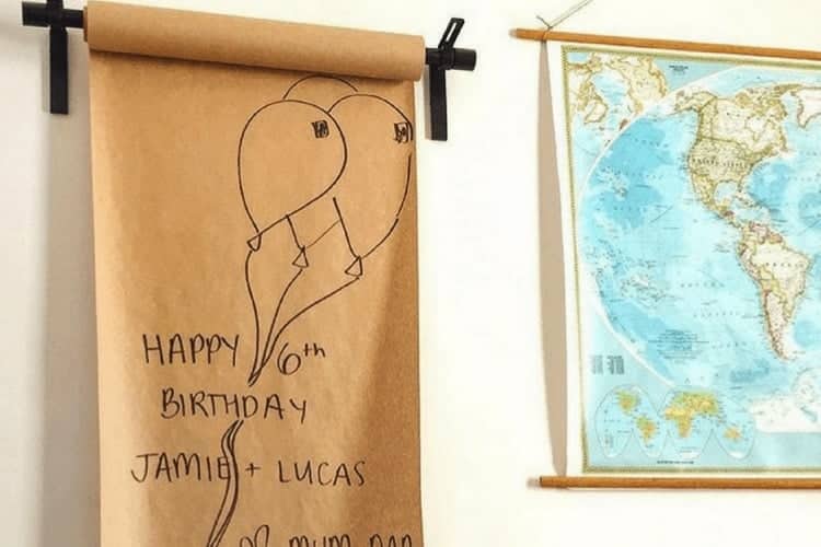 Kraft paper roll on a pink wall. Paper roll is held up by curtain brackets to create an art wall for kids or adults to draw and paint