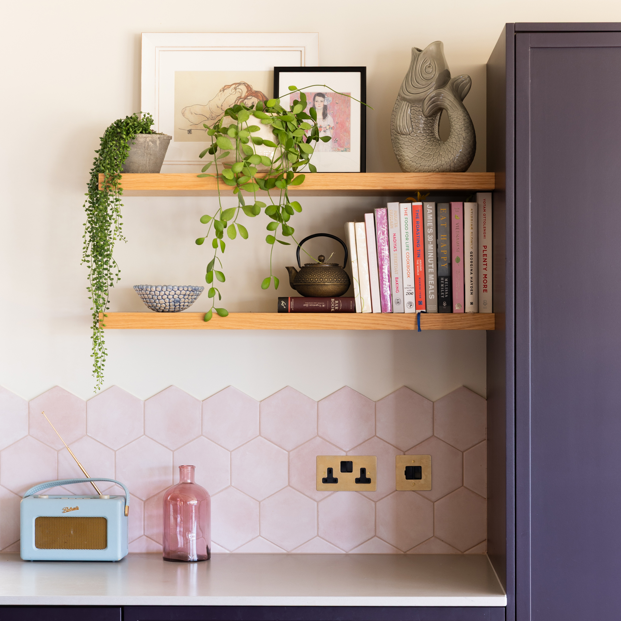 a kitchen with purple cabinets and a pale pink hexagonal tiled splashback