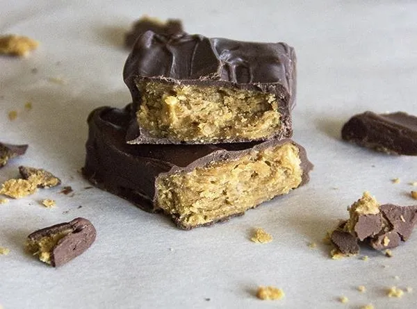 Chocolate-covered snack bar broken in half, revealing a layered filling.