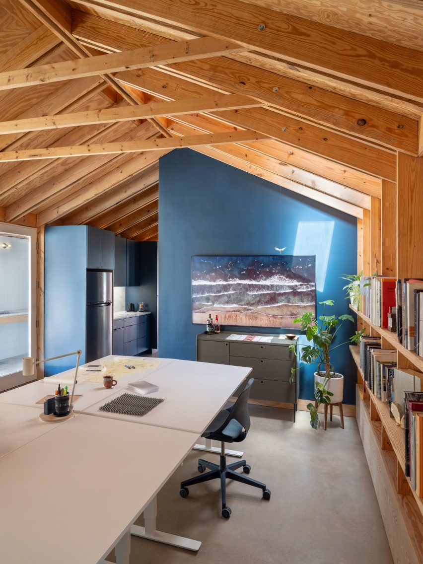 Deep blue kitchen and the bathroom exterior that contrasts an exposed timber structure