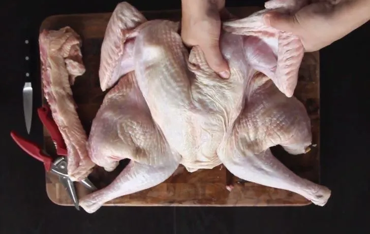 Raw whole chicken being prepared for cooking.