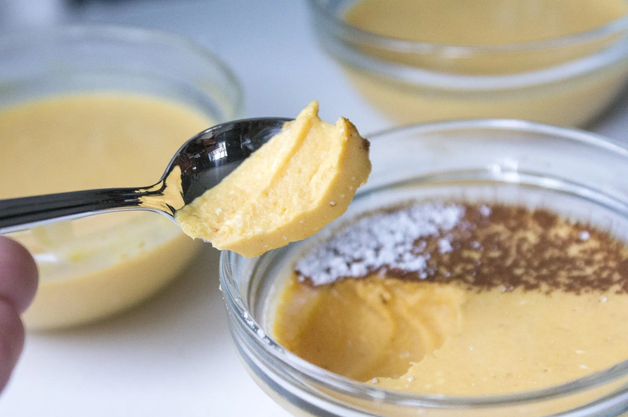 Creamy dessert in a glass dish with a spoonful being lifted.