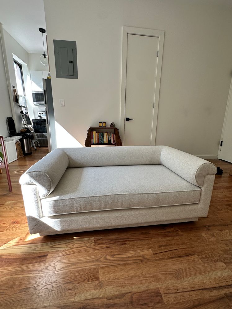 White roll arm couch in a living room with wood floors.