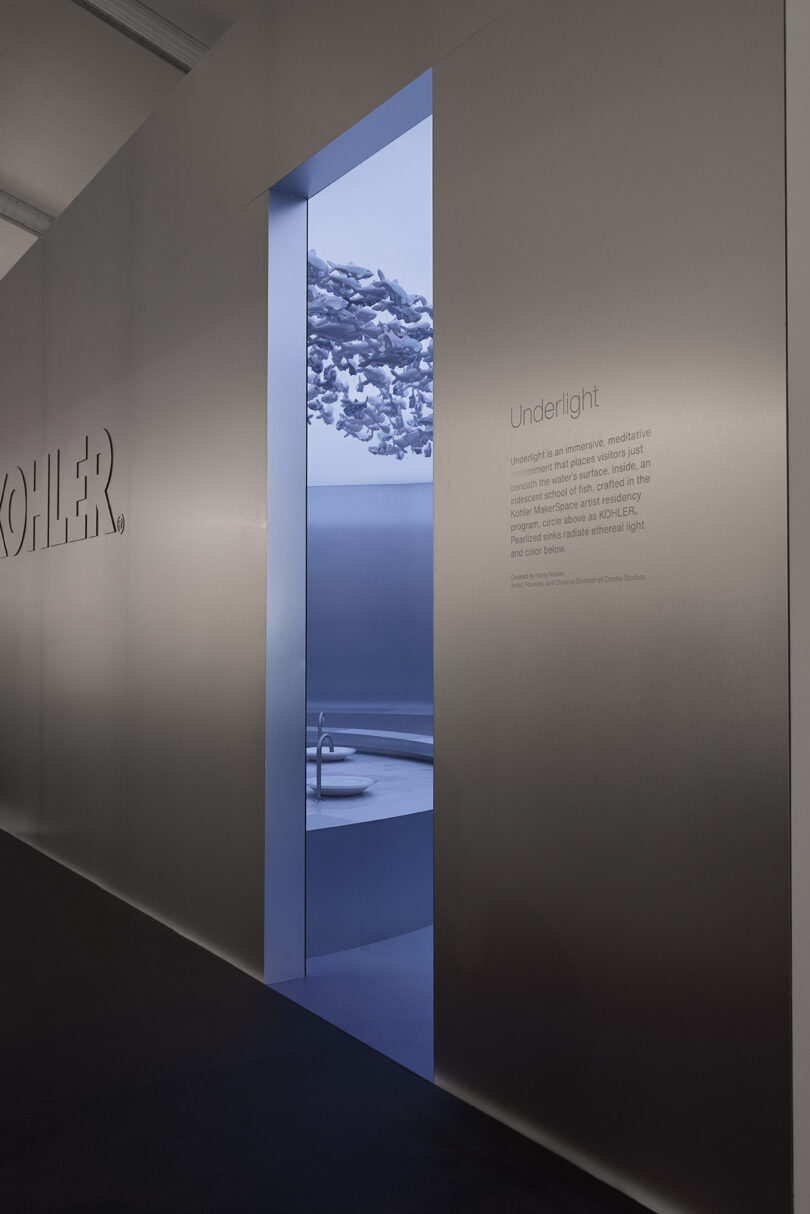 A minimalist room with a round sink is visible through a doorway, lit by soft blue light with sculptural elements on the ceiling. The wall displays the word "KOHLER" and text about "Underlight.