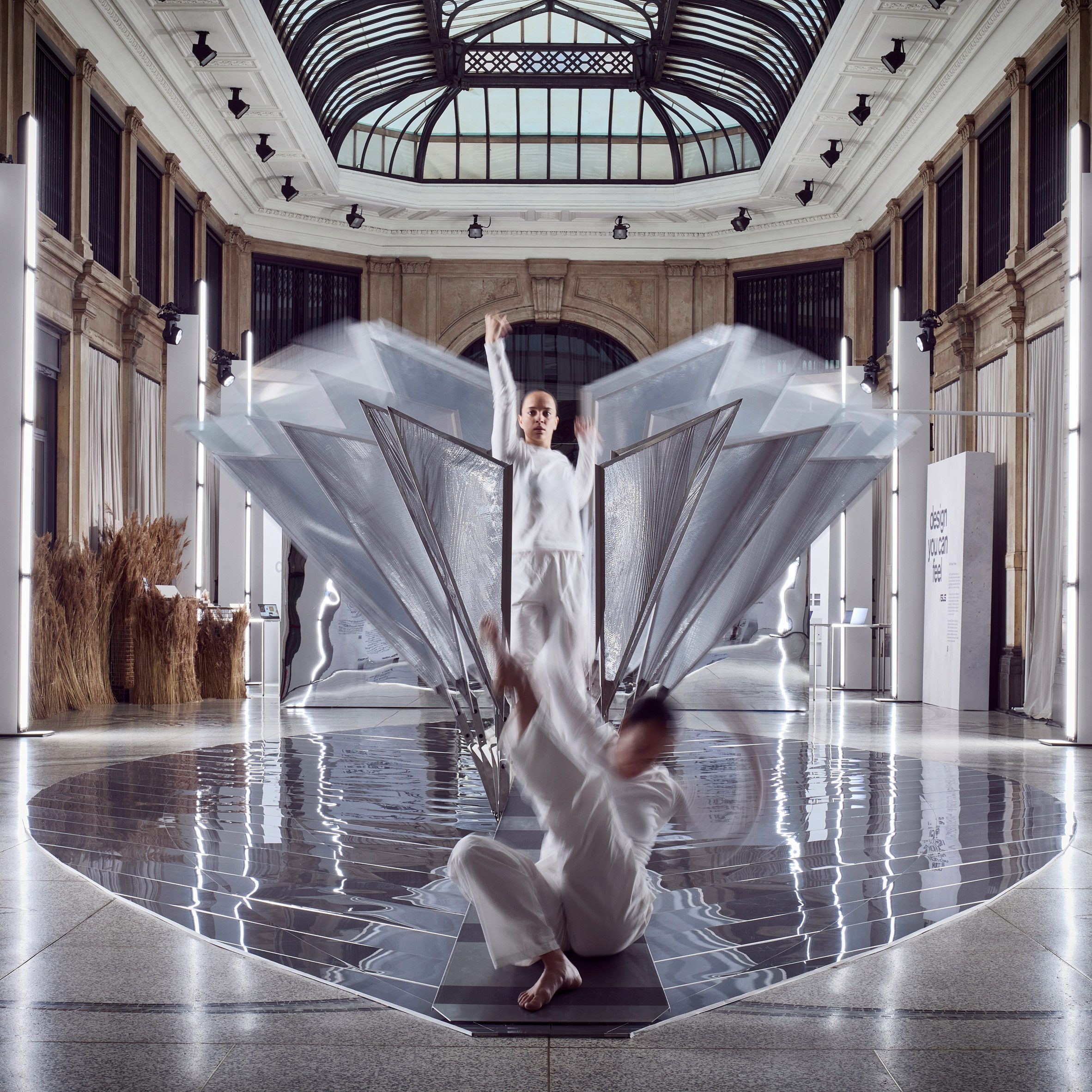 Dancers performing within winged metal installation