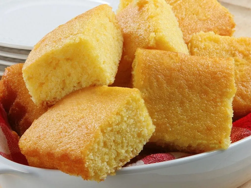 Freshly baked cornbread squares served on a white plate.