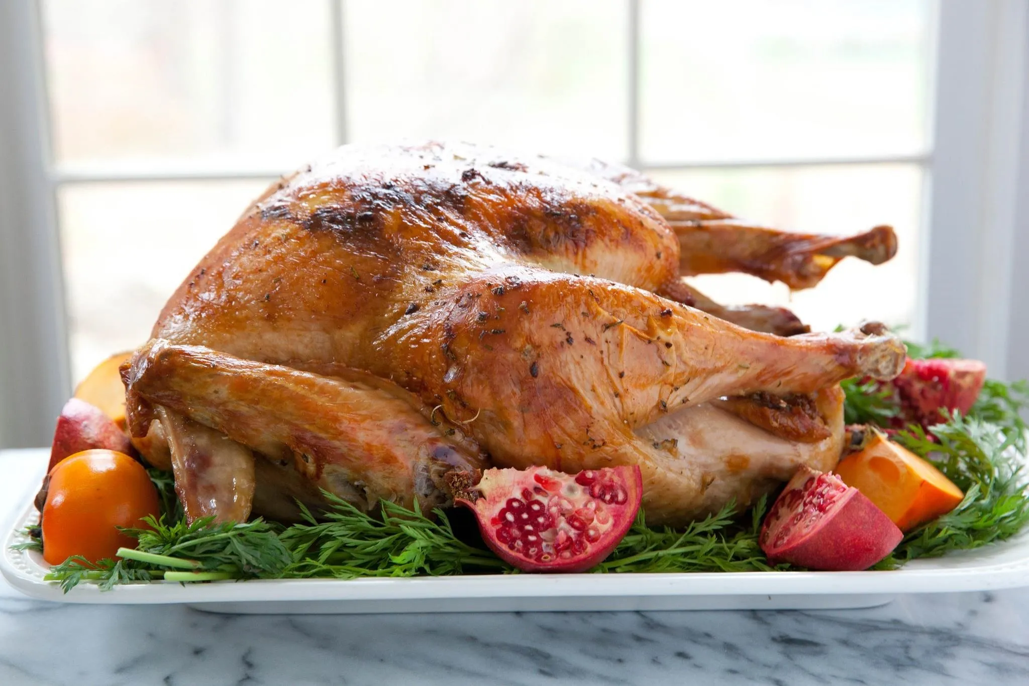 Roasted turkey garnished with pomegranate and citrus fruits.