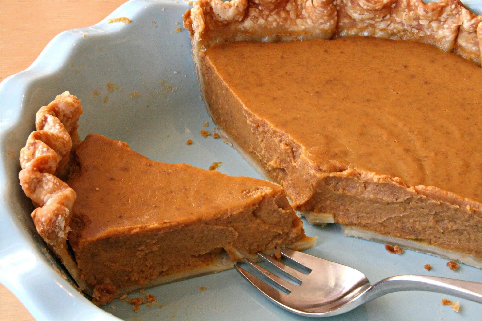 Pumpkin pie with a slice removed and a fork.