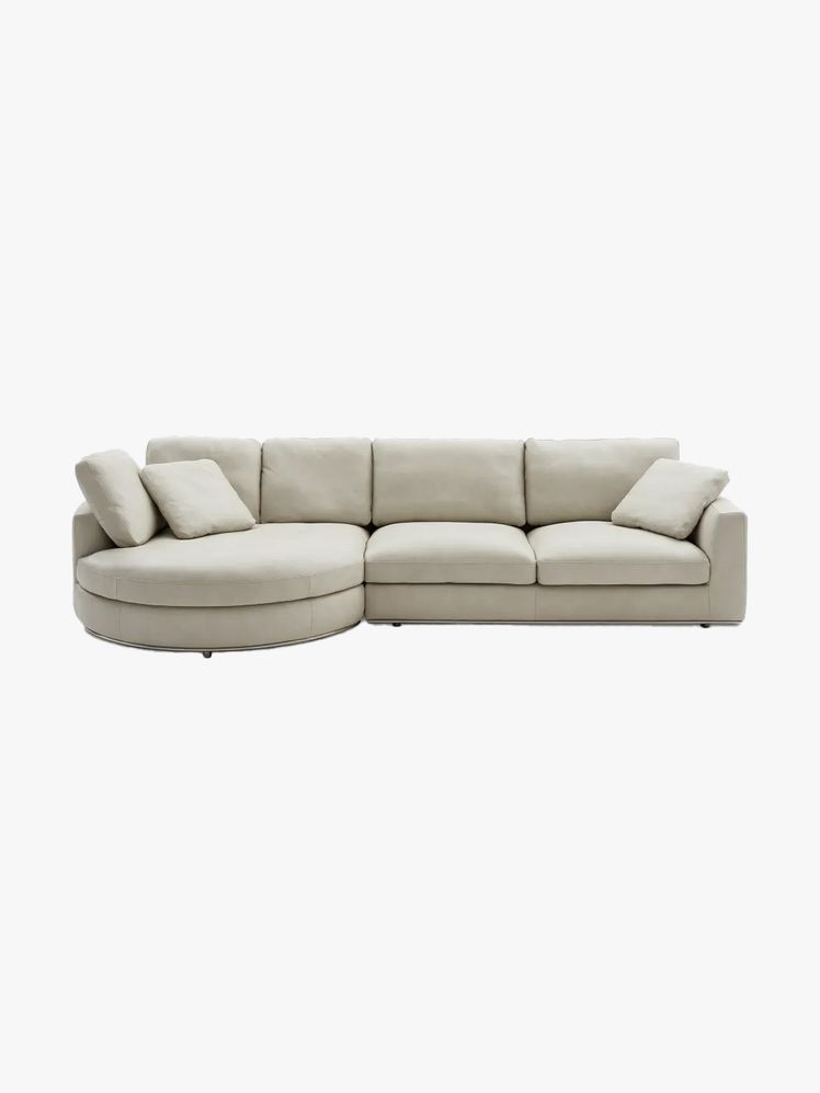 Sectional sofa with a rounded chaise on one end in beige leather.