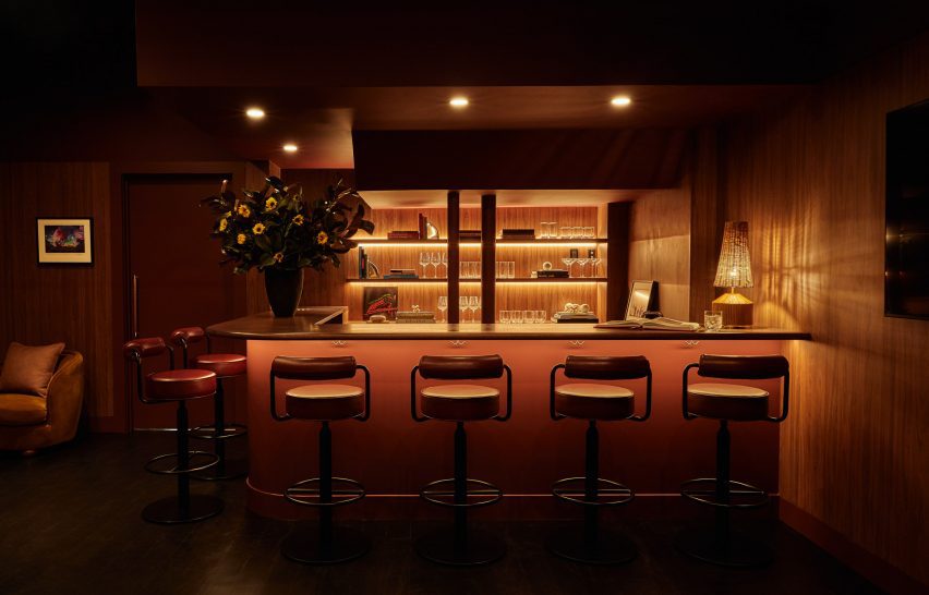 A speakeasy area decorated in darker burgundy tones, complemented by wood panelling