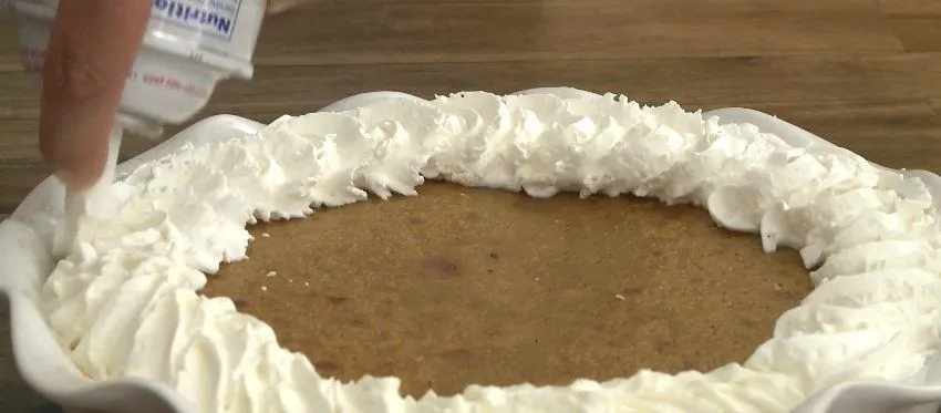 A pie with a decorative whipped cream border.